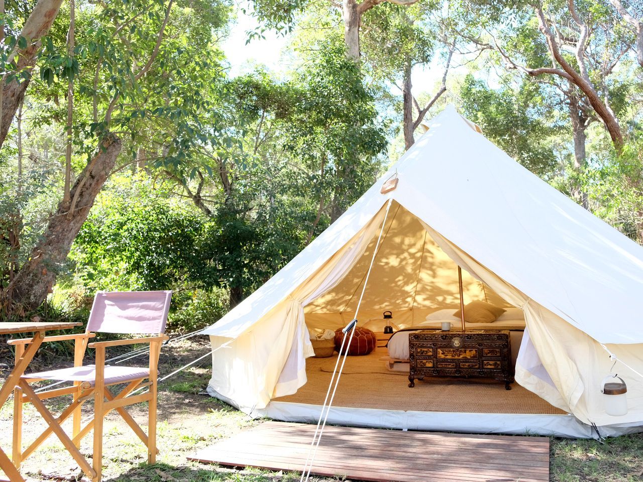 A tent with a bed, a dresser, and a chair.