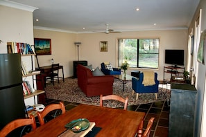 A living room with a dining table, two sofas, a TV, and a bookshelf.