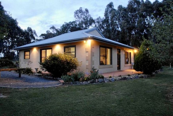 A single-story house with a flat roof, large windows, and a well-maintained lawn.