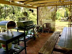 Eine Außenpatio mit Grill, Pizzaofen und Tisch mit Stühlen.