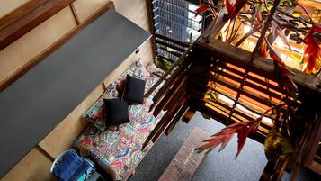 A room with a sofa, a chair, a small table, and a hanging plant.