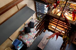 A room with a sofa, a chair, a small table, and a hanging plant.