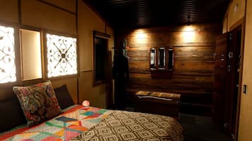 A cozy room with a bed, a bench, and a wooden wall with a mirror.