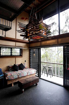 A room with a sofa, a hanging light fixture, a window, and a balcony.