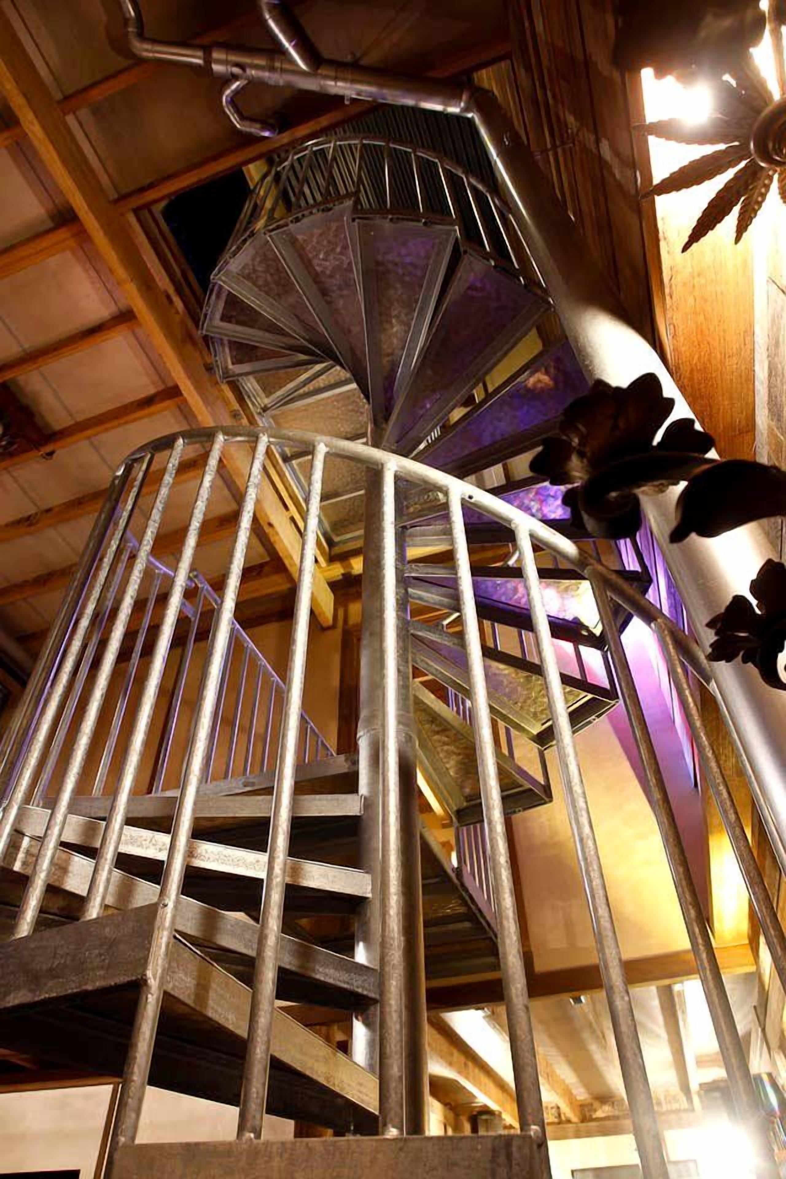 A spiral staircase with metal railings and a decorative ceiling fan.