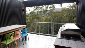Un balcón con una parrilla, una mesa y sillas de colores.
