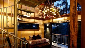 Un dormitorio con cama, ventana, balcón y escalera.