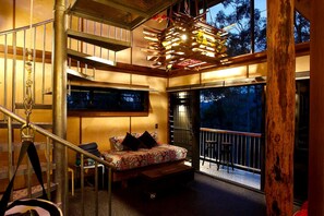 A bedroom with a bed, a window, a balcony, and a staircase.