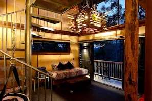 A bedroom with a bed, a window, a balcony, and a staircase.