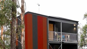 Un edificio de varios pisos con un balcón en el nivel superior.