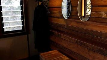 A room with wooden panel walls, a bench, and two wall-mounted mirrors.