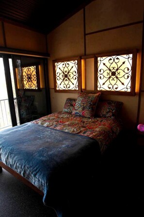 A bedroom with a bed, patterned bedding, and decorative window grills. - Amazing Gold Coast Tree House Perfect for Glamping in Queensland (Gold Coast)