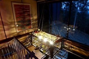 Una habitación con un ventanal grande, una planta colgante y un cuadro abstracto enmarcado.