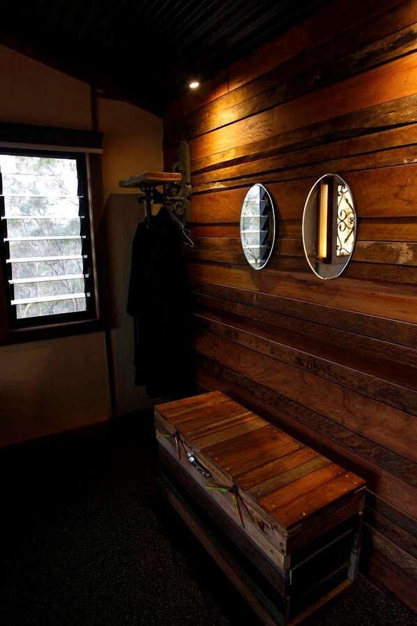 A room with wooden panel walls, a bench, and two wall-mounted mirrors.