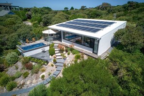 A modern house with a swimming pool, solar panels, and a patio area.