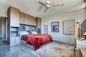 Ein Schlafzimmer mit Bett, Deckenventilator und Kunstwerken an den Wänden.