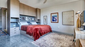 A bedroom with a bed, a ceiling fan, and artwork on the walls.