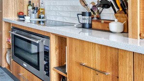 A kitchen with wooden cabinets, a stainless steel range hood, a microwave, and a countertop with various kitchen items.