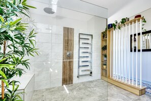Ein modernes Badezimmer mit Duschkabine aus Glas, einem hölzernen Handtuchhalter und einer weißen Fliesenwand.