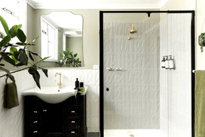 Ein Badezimmer mit einem weißen Waschbecken, einem Spiegel, einer Dusche und einem grünen Handtuch.