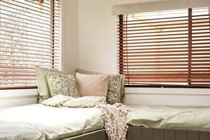 A small, cozy room with a single bed, a window with blinds, and a radiator.