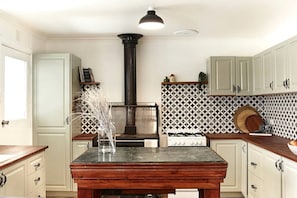 Una cocina con armarios blancos, una isla central, una estufa a gas y un salpicadero decorativo.