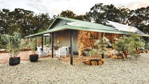 Un bâtiment rustique en pierre, doté d’un patio couvert et d’un espace extérieur aménagé pour s’asseoir.