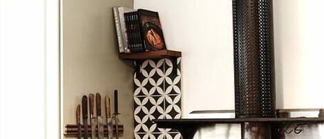 Una cocina con estufa negra, armarios blancos y un azulejo decorativo en la pared.