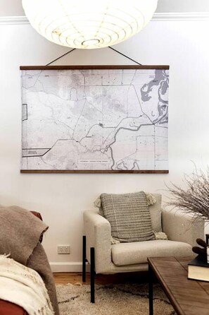 A map artwork on a wall, a sofa, a table, and a lamp. - Sweet Off-Grid Cottage with Modern Interior and Exterior in Victoria (Bailieston)