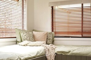 A small, cozy room with a single bed, a window with blinds, and a radiator. - Sweet Off-Grid Cottage with Modern Interior and Exterior in Victoria (Bailieston)