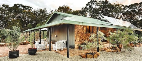 A rustic stone building with a covered patio and outdoor seating.