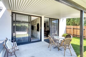 A covered patio with a table and chairs, a bench, and a sliding glass door leading to an interior space.