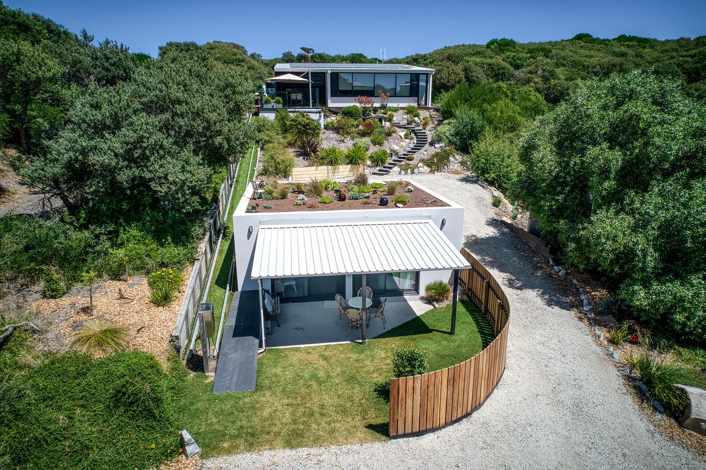 A modern house with a covered patio, a garden, and a driveway.