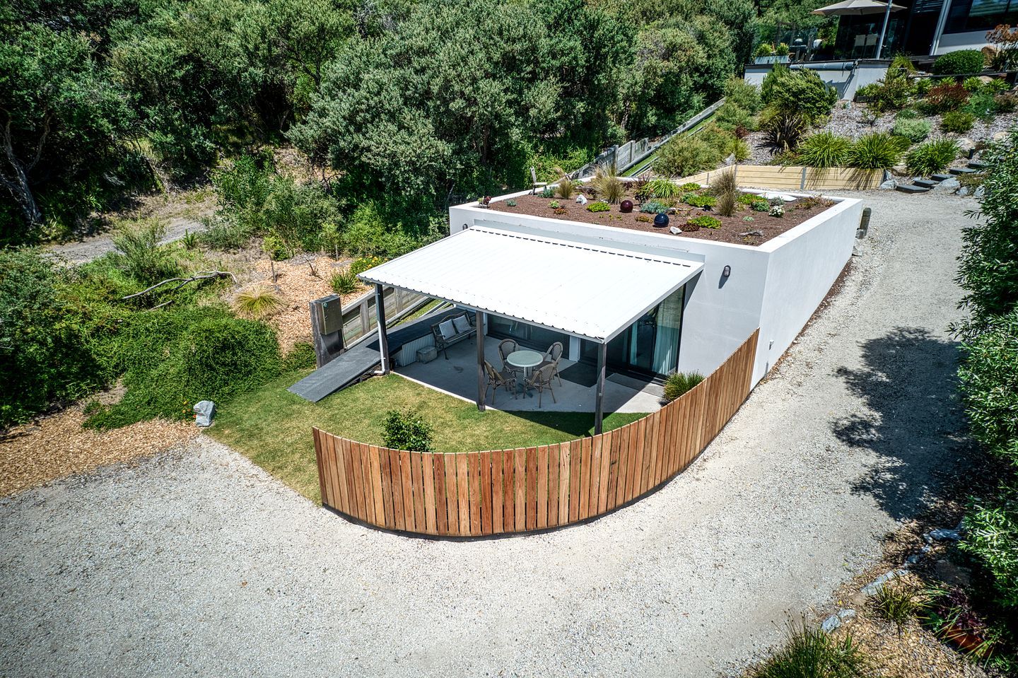 Uma casa moderna com telhado plano, alpendre coberto e cerca de madeira.