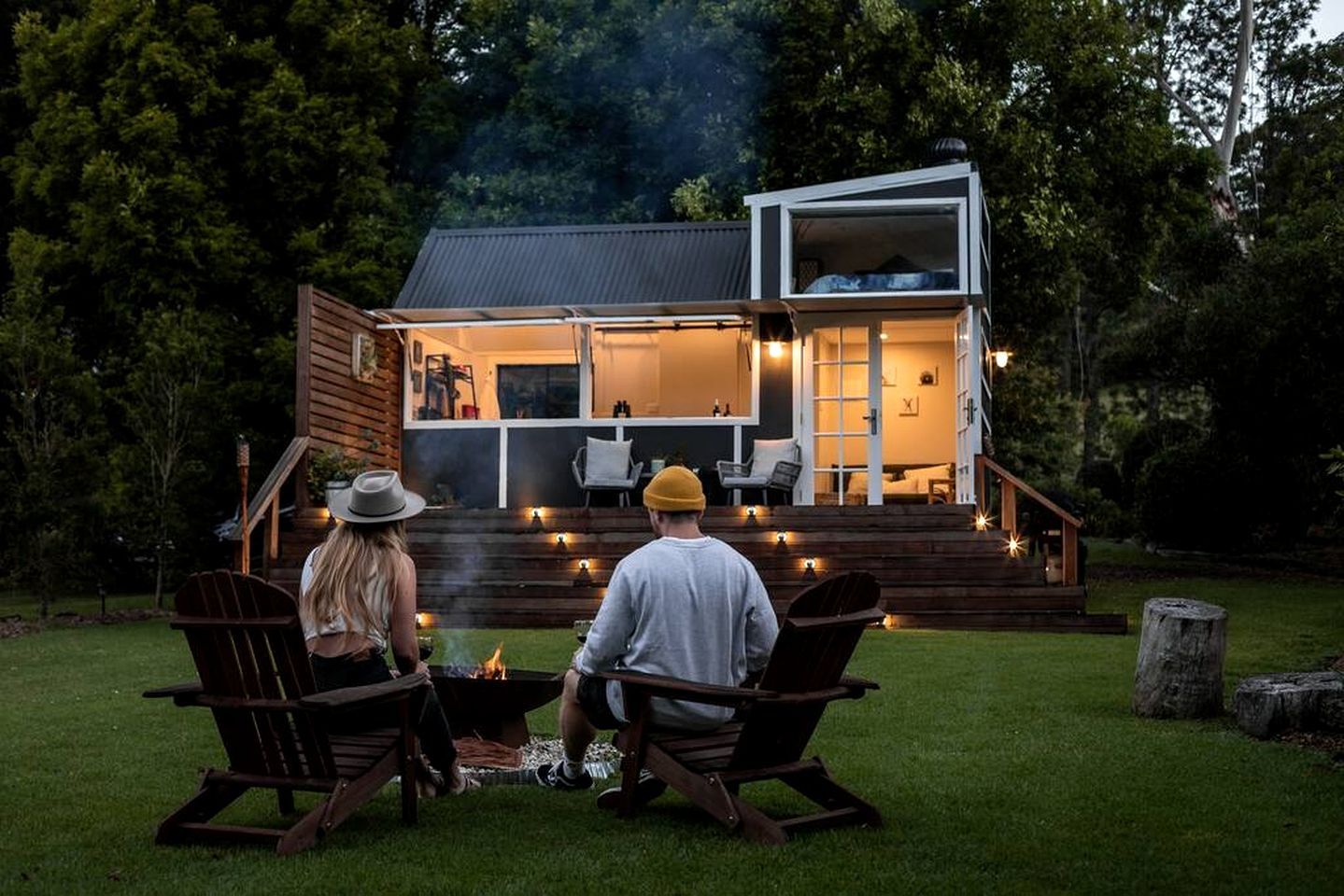 A two-story house with a deck and a fire pit in the backyard.