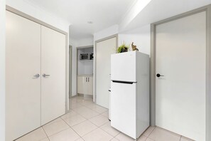 A hallway with a white refrigerator, a microwave, and a cabinet.