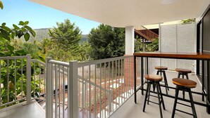 A balcony with a white railing, a wooden table, and three bar stools.