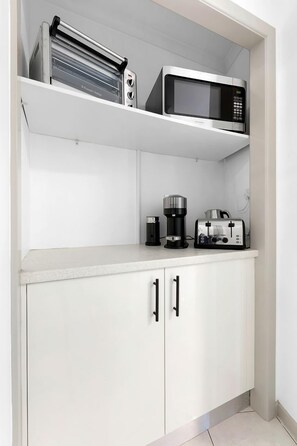 A kitchenette with a microwave, toaster, and coffee maker on the countertop.