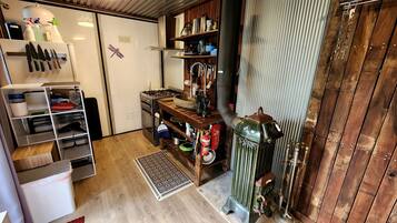 Eine kompakte Küche mit einem Gasherd, Holzböden und einer Espressomaschine im Vintage-Stil.