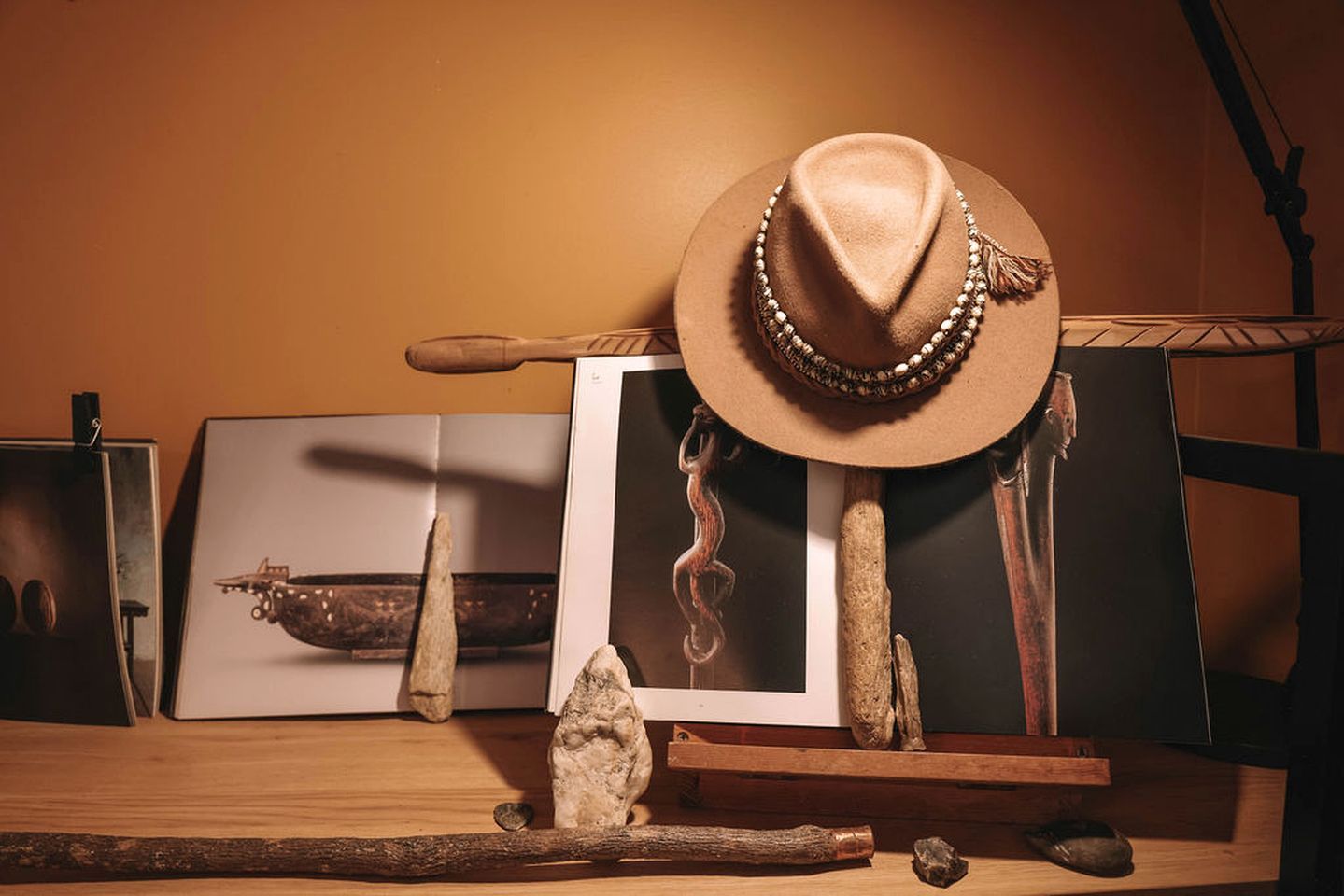 Un interior rústico con un sombrero sobre un soporte, herramientas de madera y un cuadro enmarcado.