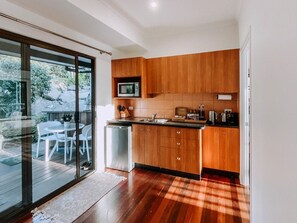 A modern kitchen with wooden cabinets, a built-in microwave, and a dishwasher. - Secluded Mountain Cabin with Private Sauna & Ice-Bath Near Springbrook, Mudgeeraba, Queensland (Mudgeeraba)