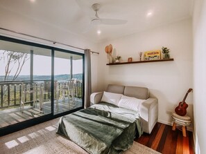 A bedroom with a bed, a guitar, a shelf with items, and a balcony with a view. - Secluded Mountain Cabin with Private Sauna & Ice-Bath Near Springbrook, Mudgeeraba, Queensland (Mudgeeraba)
