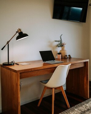Un bureau en bois avec un ordinateur portable, une lampe et une plante en pot.