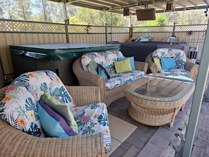 An outdoor patio area with wicker furniture, a glass-top table, and a barbecue grill.
