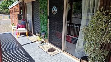 A covered outdoor seating area with a table and chairs, a potted plant, and a door with a security screen.