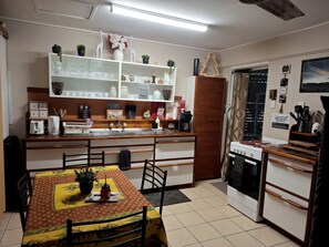 Una cocina compacta con una mesa de comedor, horno empotrado y un armario blanco con puertas de vidrio.