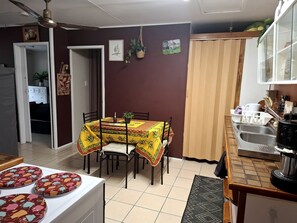 A dining area with a table covered in a yellow tablecloth, surrounded by chairs.