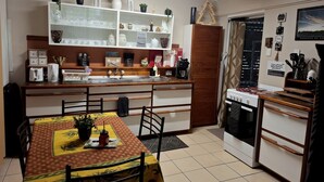 Una cocina compacta con una mesa de comedor, horno empotrado y un armario blanco con puertas de vidrio.