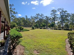 A well-maintained grassy area with a pathway leading to a building, surrounded by trees and shrubs.