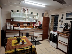 Una cocina compacta con una mesa de comedor, horno empotrado y un armario blanco con puertas de vidrio.